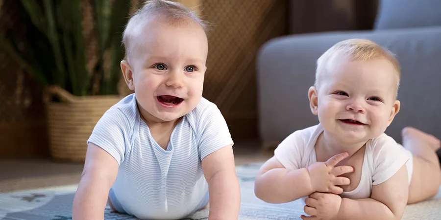 Krupni kadar beba blizanaca kako se igraju na podu sobe.