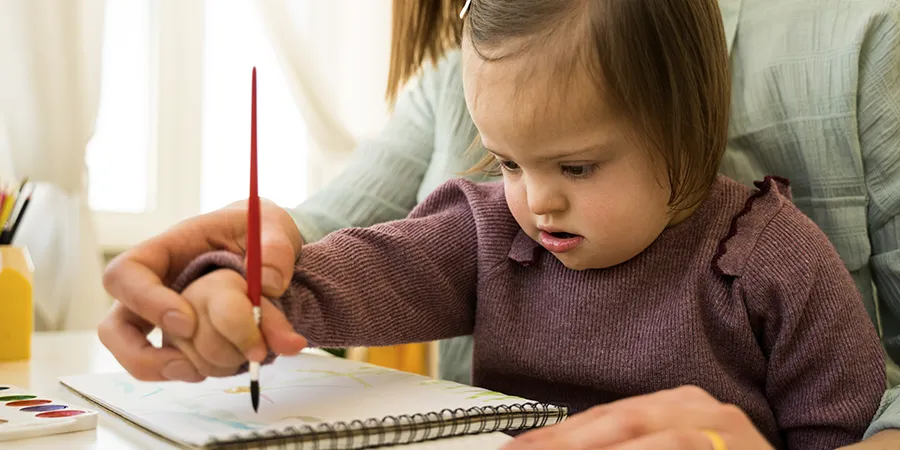 Jednogodišnja devojčica slika svoj prvi umetnički rad uz maminu pomoć.