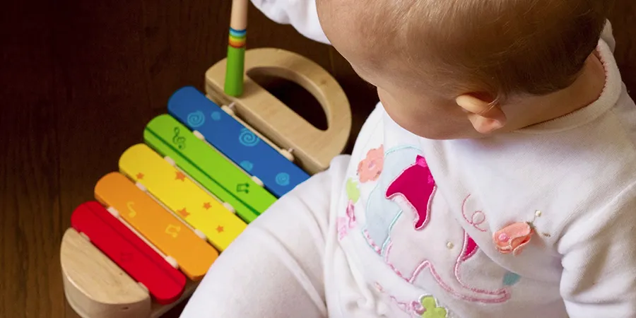 Krupni kadar bebe odozgo koja se igra sa ksilofonom.
