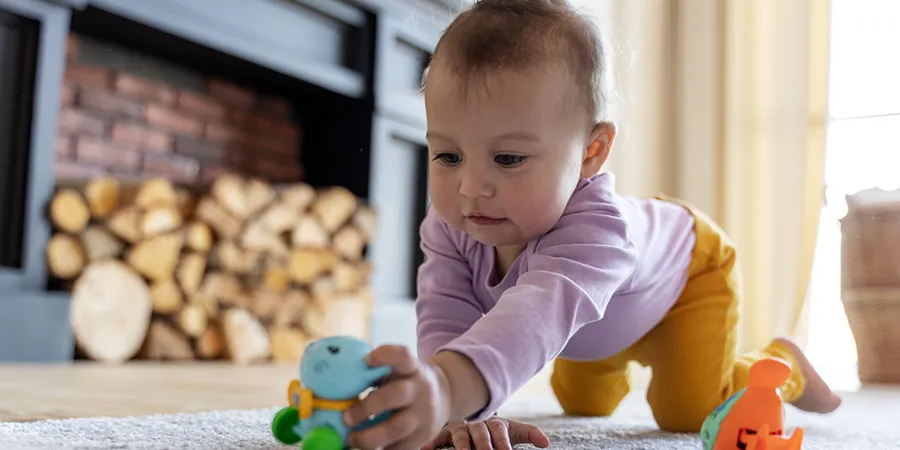 Prelatka beba se igra svojim igračkama na podu svog doma.