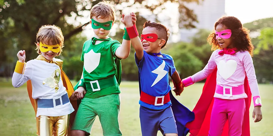 Četvoro dece, poziraju u parku, obuceni u šarene kostime inspirisane superherojima.