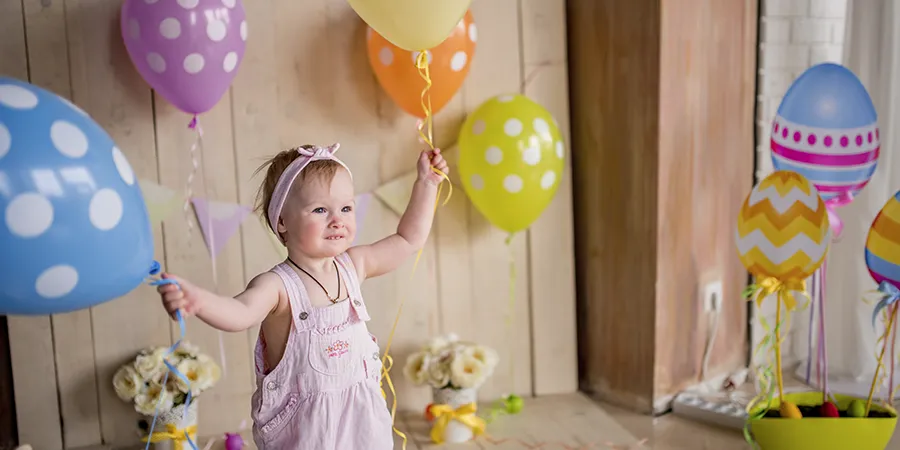Slatka mala devojčica izgleda srećno dok drži šarene balone.