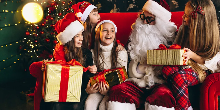 Grupa devojčica dobija poklone od Deda Mraza.