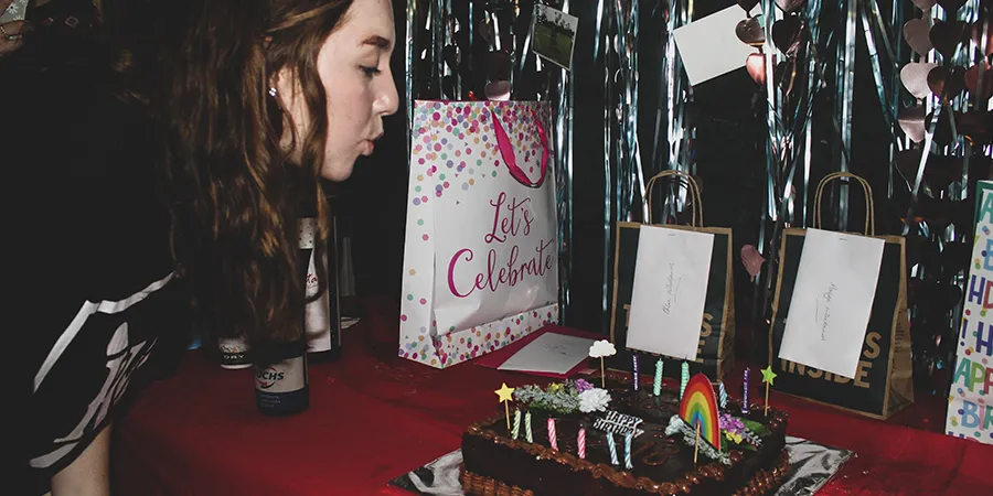 Devojka duva svećice na svojoj rođendanskoj zabavi.