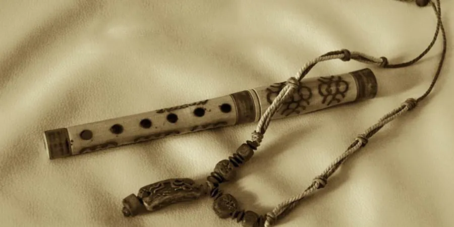 Fotografija frule i tradicionalne ogrlice, na svetloj pozadini izdađene od kože.
