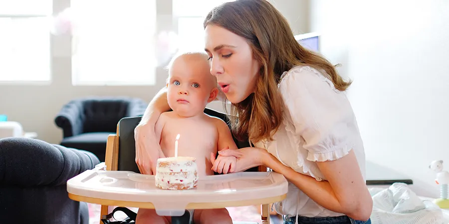 Mama i beba proslavljaju prvi rođendan. Beba sedi u hranilici, ispred nje se nalazi mala torta sa svećicom, koju mama duva.