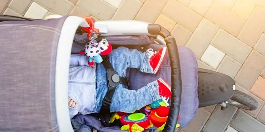 Beba u kolicima okružena igračkama. Kadar odozgo. 