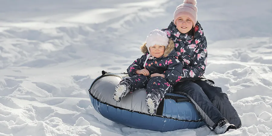Dve sestrice uživaju u zimskim čarolijama sa gumom na snegu.