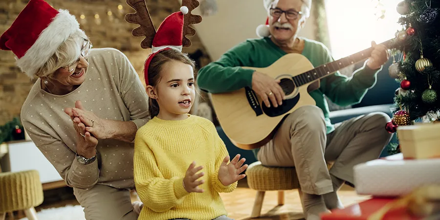 Baka i deka pevaju božićne pesmice za svojom unukom.